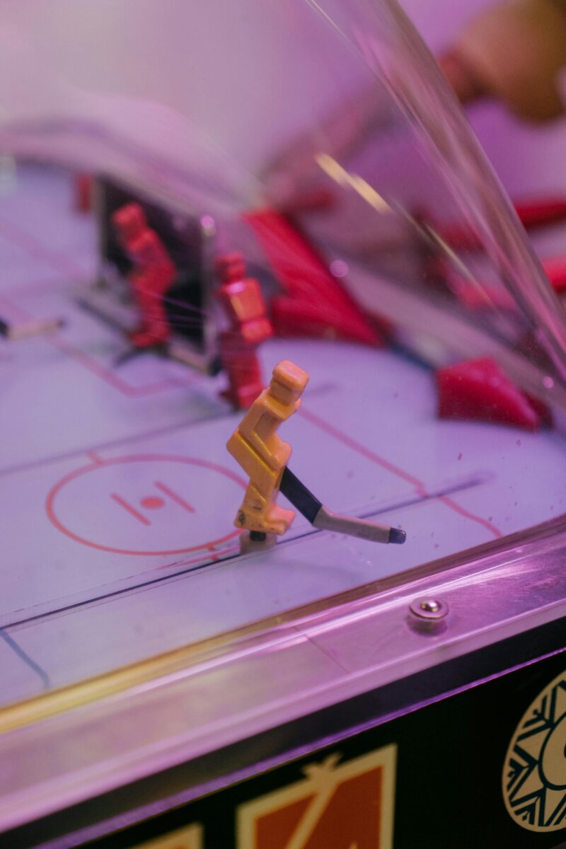 A vibrant, retro table hockey game with plastic players inside a protective dome.